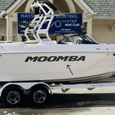 White Moomba boat on a trailer in front of a building with a sign for Hassett Boating Suntex Boat Club.